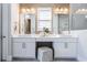 Bright and modern bathroom with double vanity, white cabinets, two mirrors and gray wood-look flooring at 16728 Bolsena Dr, Bella Collina, FL 34756