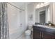 Well-lit bathroom with a shower-tub, white tile walls and a dark vanity with modern fixtures at 16728 Bolsena Dr, Bella Collina, FL 34756