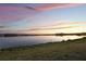 Scenic lake view with colorful sunset backdrop and lush grass at 16728 Bolsena Dr, Bella Collina, FL 34756