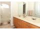 Bathroom with double sink vanity, mirror, wood cabinets, and a view of the tiled tub and shower at 1924 Stonecrest Ct, Orlando, FL 32825