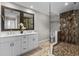 Modern bathroom featuring dual sinks, decorative mirrors, and a glass-enclosed tiled shower at 230 S Ranger Blvd, Winter Park, FL 32792