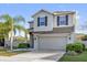 Charming two-story home featuring a well-manicured lawn, palm tree, and a two car garage at 3179 Turret Dr, Kissimmee, FL 34743