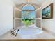 Bright bathroom featuring soaking tub under arched window overlooking lush greenery at 3431 Dawn Ct, Lake Mary, FL 32746