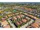 An aerial view showing a residential community with tile roofs, mature trees, swimming pool, and recreational area at 5283 Wildwood Way, Davenport, FL 33837