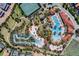 Aerial view of community pool and lazy river, featuring tennis courts and lush landscaping at 5283 Wildwood Way, Davenport, FL 33837