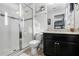 Bathroom featuring a glass-enclosed shower with tiled accents, granite countertop, and dark cabinetry at 5283 Wildwood Way, Davenport, FL 33837