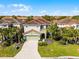 A two-story home with a tile roof, well-manicured lawn, and tropical landscaping at 5283 Wildwood Way, Davenport, FL 33837