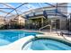 A view of the screened-in pool and spa from an elevated vantage point, with patio seating and a second-story balcony at 5283 Wildwood Way, Davenport, FL 33837