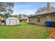 A storage shed and blue recycling container sit in the green backyard behind the house at 600 Statenville Ct, Ocoee, FL 34761