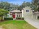 Charming two-story home with a well-manicured lawn, red front door, and three-car garage at 600 Statenville Ct, Ocoee, FL 34761