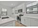 Well-lit, all-white kitchen with quartz countertops, subway tile backsplash, and stainless steel appliances at 62 W Jersey St # 13, Orlando, FL 32806