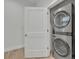 Bright laundry room with stacked washer and dryer, and a white door to the outside at 62 W Jersey St # 13, Orlando, FL 32806