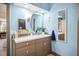 A charming bathroom with light blue walls, a vintage vanity, round mirror, and decorative coastal accents at 7279 Nena Ct, Mount Dora, FL 32757