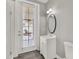 Bathroom features a vanity sink, toilet, shower, door leading to the outside, and an oval mirror at 7548 Gathering Dr, Reunion, FL 34747