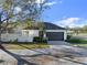 Side view of home showcasing a garage with a driveway, landscaping, and a partial view of the front yard at 7548 Gathering Dr, Reunion, FL 34747