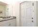 Half bath features a granite countertop vanity, a decorative mirror, and white paneled door at 7699 Oakmoss Loop, Davenport, FL 33837