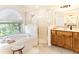 Bathroom featuring dual sinks, a walk-in shower, and a garden tub with a view of the mature landscaping at 814 Chamberlin Trl, St Cloud, FL 34772