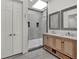 Bathroom featuring a glass shower, double sink vanity with framed mirrors and stylish baskets at 10148 Chiltern Garden Dr, Orlando, FL 32827