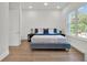 Bright bedroom boasts wood flooring, a stylish bed frame, and a large sunlit window at 10148 Chiltern Garden Dr, Orlando, FL 32827