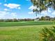 Picturesque golf course view featuring lush green grass, mature trees and a modern clubhouse at 10148 Chiltern Garden Dr, Orlando, FL 32827