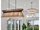 Modern chandeliers are suspended above large windows providing views of the outdoors, with green foliage at 10148 Chiltern Garden Dr, Orlando, FL 32827