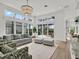 Bright living room with large windows, neutral sofa, patterned chairs, and views of the outdoor patio at 10148 Chiltern Garden Dr, Orlando, FL 32827