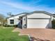 View of the two-car garage, a brick driveway, and a green lawn of a well-maintained one-story home at 120 Mayfair Ct # 120, Sanford, FL 32771
