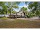 A charming home's backyard with a wooden deck, set against a backdrop of mature trees and partial fencing at 1401 E Voorhis Ave, Deland, FL 32724