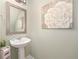 Well-lit half bathroom featuring a pedestal sink, decorative mirror, and neutral paint, creating a clean space at 1625 Smokey Oak Way, Longwood, FL 32750