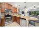 Modern kitchen featuring stainless steel appliances, wooden cabinetry, granite countertops, and pendant lighting at 1625 Smokey Oak Way, Longwood, FL 32750