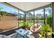 Relaxing sunroom featuring a comfortable chair, glass table, and lush green plants with a scenic backyard view at 1625 Smokey Oak Way, Longwood, FL 32750