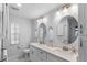 Bright bathroom featuring dual sinks with round mirrors, white cabinetry, and stone countertops at 17 Hibiscus Ct, Eustis, FL 32726