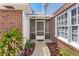 Covered townhouse entryway with a screen door, brick accents, and vibrant flowerbed at 17 Lawn St, Oviedo, FL 32765