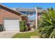 Townhouse exterior featuring brick facade, white garage door, and a walkway surrounded by greenery at 17 Lawn St, Oviedo, FL 32765