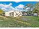 Spacious backyard with lush green grass and an adjacent building, under a bright sky filled with fluffy clouds at 226 Noxon St, Auburndale, FL 33823