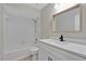 Bright bathroom featuring a shower-tub combo, a wooden-framed mirror, and a sleek white vanity with modern fixtures at 226 Noxon St, Auburndale, FL 33823