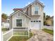 Inviting two-story home boasts a clean white garage door, stucco finish, and charming white picket fence at 2361 Carriage Run Rd, Kissimmee, FL 34741