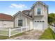 Inviting two-story home featuring a white picket fence, tidy lawn, and an attached garage at 2361 Carriage Run Rd, Kissimmee, FL 34741