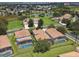 Aerial view of several homes with screened pools and lush landscaping near a pond with a fountain at 2631 Archfeld Blvd, Kissimmee, FL 34747