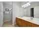Bathroom vanity featuring dual sinks, large mirror, and walk-in shower with glass doors at 2631 Archfeld Blvd, Kissimmee, FL 34747
