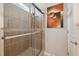 Tiled walk-in shower behind sliding doors with neutral toned art work in renovated bathroom at 2631 Archfeld Blvd, Kissimmee, FL 34747