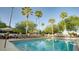 Lounge chairs and tables arranged around a crystal-clear pool with palm trees at 3000 Maingate Ln # 520, Kissimmee, FL 34747