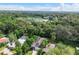 Aerial view showcases a well-maintained home with a private pool surrounded by lush greenery and a lake at 322 N Rhodes St, Mount Dora, FL 32757