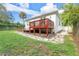 A backyard showcasing a raised wood deck, lush lawn, and mature landscaping with stone pathways enhancing the outdoor space at 322 N Rhodes St, Mount Dora, FL 32757