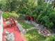 The aerial view of the backyard shows a deck, a pergola, a fire pit, and stone paths amongst the lush landscaping at 322 N Rhodes St, Mount Dora, FL 32757