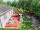 Aerial view of a backyard featuring a deck, pergola, stone pathway, fire pit and lush landscaping providing a serene outdoor oasis at 322 N Rhodes St, Mount Dora, FL 32757