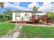 Charming backyard featuring a wooden deck with patio furniture and stone pathways leading to a well-maintained lawn and garden at 322 N Rhodes St, Mount Dora, FL 32757