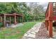 Backyard view of a wooden pergola featuring a grill, seating area, and a stone pathway leading to a beautifully landscaped garden at 322 N Rhodes St, Mount Dora, FL 32757