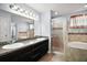 Large bathroom with double granite sink and shower over tub with glass door at 328 Woodland Trl, Lady Lake, FL 32159
