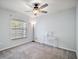 Bright bedroom featuring plush carpet, ceiling fan, and a large window for natural light at 328 Woodland Trl, Lady Lake, FL 32159